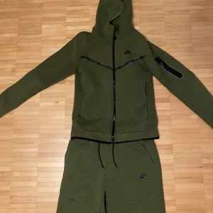 Olivgrön Nike Tech Fleece  - Säljer hela min tracksuit i storlek M i änvänt skick. Nypris ligger på 2200kr men säljer båda delarna tillsammans för 900kr (Lappen på koftan är borttagen då den skavde för nacken)
