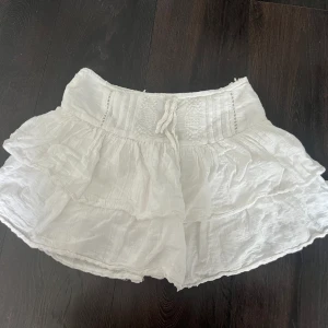 Kjol - Broderi och rosett fram med volanger, inbyggda shorts