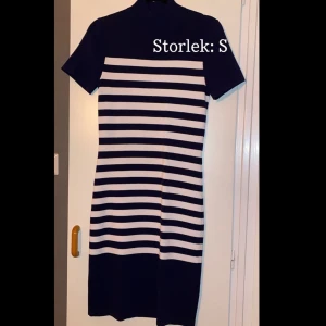 Stickad & klassisk, Micheal kors klänning   - En marinblå, vitrandig, kroppsformad klänning med en mindre turtle neck, från Micheal kors. Längden är nertill vaderna. Klänningen är i ett varmare material.  Nästintill oanvänd, fläckfri och inga hål. Klänningen är inte urtvättad.    Exl.frakt 