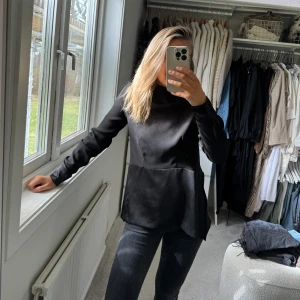 Svart blus med knyt där bak, slits på sidor. H&M.  - Svart blus med höghals, knytning där bak samt slits på sidorna.  Storlek 34. 
