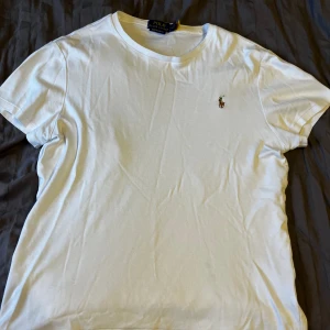 Ralph lauren T-shirt slim fit i vit, storlek M  - Säljer nu denna fina ralph lauren T-shirt i vit då jag inte använder den längre. Den är i 10/10 skick, inga hål eller skador osv. Hör gärna av er vid fler frågor eller om ni vill ha fler bilder på plagget:)