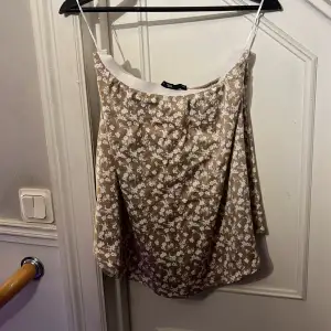 En brun-blommig kjol från lager127. Aldrig använd. Kjolen har en vit resår (se bild) som du viker in kanten på.