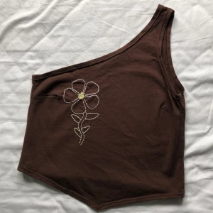 Oneshoulder linne/topp - Oneshoulder linne med en brodrerad blomma. Skönt material, tänkte sy om den men säljer den istället då den är större än jag vill ha den, så den är i princip helt oanvänd.