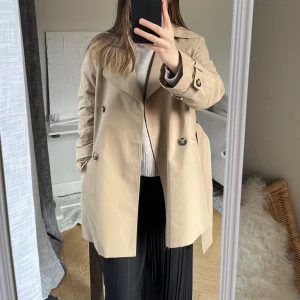 Kort trenchcoat - Superfin trenchcoat i kortare modell från H&M. Säljer då jag har en till liknande. Har mindre märken vid armbågen, annars fint skick. Perfekt jacka till vår och höst 💛✨