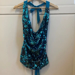 Halternecktopp med pajetter - Asfin festtopp i typ blå/turkos färg. Går att knyta både i ryggen och runt halsen så passar alla möjliga storlekar🫶🏼