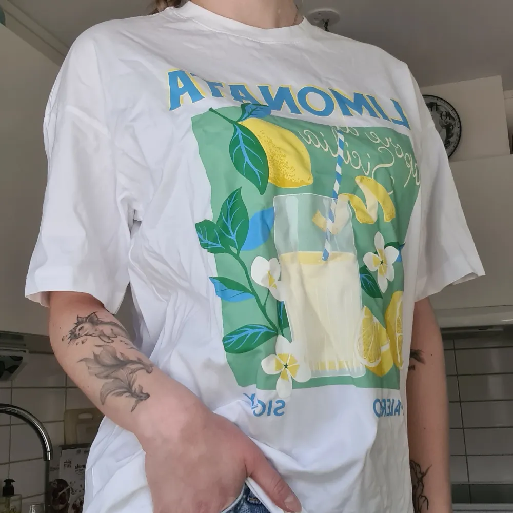 Limonata tryck på vit t-shirt. Aldrig använd, lappen kvar, nypris 199kr. Oversize modell så den är större i storleken. Kom med prisförslag 😊  Material: 100% Bomull.. T-shirts.