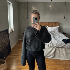 Stickad tröja med öppning i ryggen  - Mörkgrå stickad tröja från H&M med en öppning nertill på baksidan. Använd två gånger. Normal i storlek. Passar xs och S. 