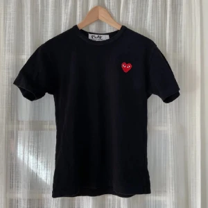 Comme Des Garçons T-shirt  - Comme Des Garçons T-shirt i svart med rött hjärta. Storlek S. Nypris ca 1000kr. Väldigt bra skick. Lånade bilder men min ser exakt likadan ut.  Skriv för fler bilder. Kan mötas upp i Stockholm annars står köparen för frakt. 🖤❤️