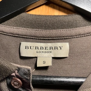 Burberry - Säljer en snygg brun burberry piké i storlek S.  Skick 7,5/10 ( finns lite vita fläckar men syns bättre på bild ) Därav Priset! Tveka inte på att höra av dig 