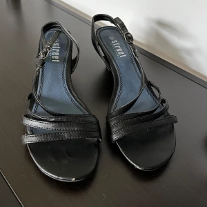 Svarta Klackskor - Svarta fina klackskor. Slita i spännbandet och bak i hälen. Passar på mig som brukar ha mellan 39-41 på klackskor! Ca 5cm klack💛 Skriv vid frågor!