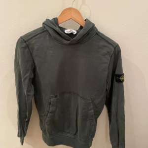 Stone island junior hoodie - Mörkgrön stone island hoodie i helt okej skick 6/10 nypriset är 1600kr och storleken är 158cm passar 12år. Priset går att diskutera.