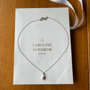 Caroline Svedbom Halsband - Jätte fint halsband i silver med en rosa sten. Caroline Svedbom som är handgjord i Grekland. Nypris 450kr. Jätte bra skik och aldrig använd. Tryck gärna köp nu
