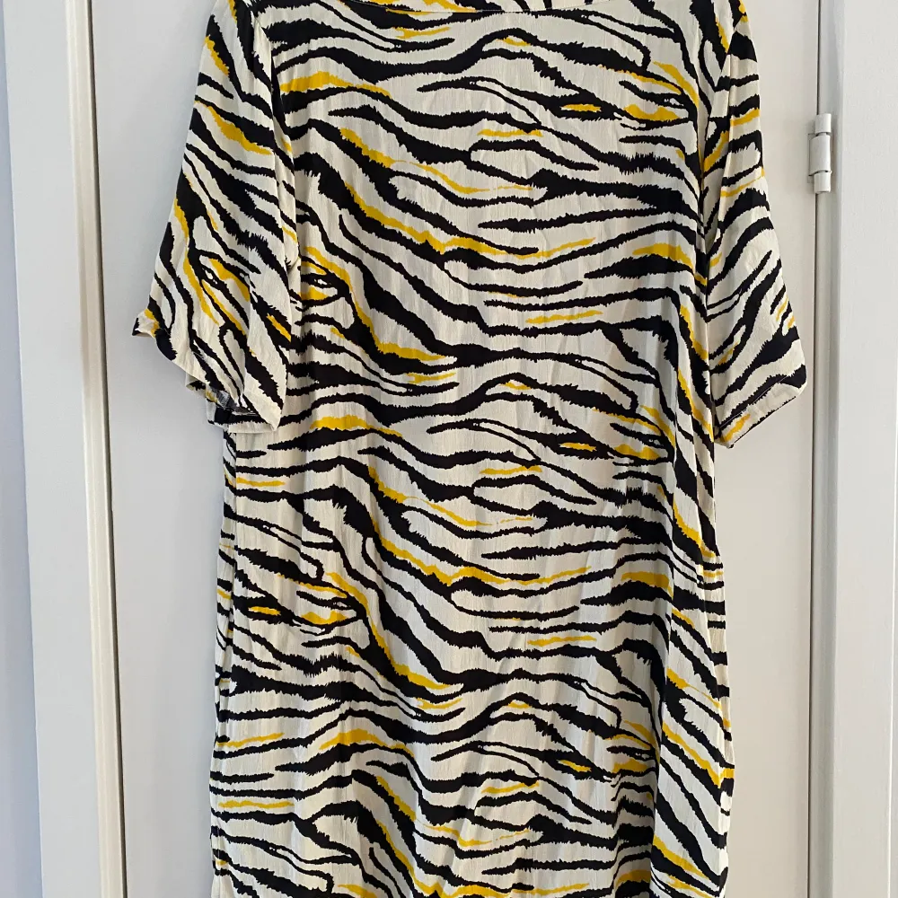 Svart, vit och gul tigermönstrad klänning fr Ahoney i strl L.  Sparsamt använd och i fint begagnat skick.  Viskos   Kommer från ett djur och rökfritt hem.. Klänningar.