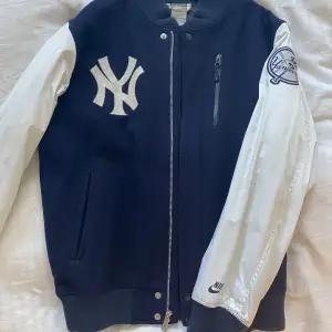 Old school vintage varsity jacka med en klassisk design. Nike i kollboration med amerikanska baseboll laget New York Yankees. Perfekt för streetwear. Armarna behöver tvättas. 