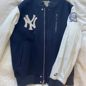 Vintage Nike New york Yankees Varsity Jacket  - Old school vintage varsity jacka med en klassisk design. Nike i kollboration med amerikanska baseboll laget New York Yankees. Perfekt för streetwear. Armarna behöver tvättas. 