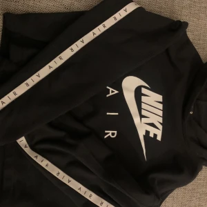Nike hoodie tonåring  - Nike luvtröja, Nikes klassiska logga över bröstet och vit remsa med Nike air längs sidan av ärmarna. Är kortare vid mage, länge magtröja.