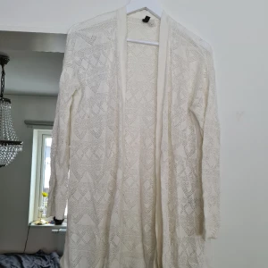 Vit kofta  - Bohemisk vit kofta med hål-mönster, lent tyg. Använd men i fint skick, normal i storlek. Kom med prisförslag 😊  Material: 50% Akryl, 50% Viskos.