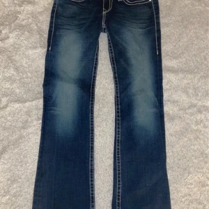 True Religion Jeans - Jättesnygga lågmidjade true religion jeans som inte kommer till andvändning då de är förstora och för långa för mig, bara använda ungefär 4-5 gånger.😽 Midjemått- 85cm Innerbenslängd-86cm