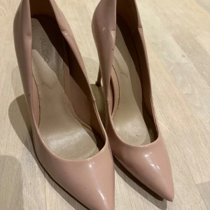 Pumps klack Aldo nude  - Pumps från Aldo i lackig nude färg. Storlek 38. Använda men i gott skick - se bilder. 