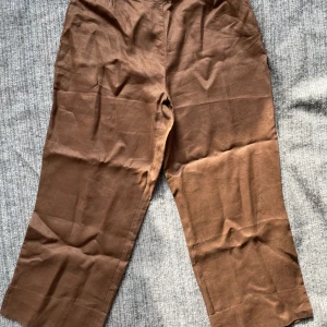 Linnebyxor M - 100% lin från Vila, storlek M. Tunna och luftiga, inte hellånga. Ca 37 cm i midjan mätt rakt över, 80 cm långa mätt på utsidan, 58 cm mätt på insidan från grenen ner. Har flera foton. Dragkedja på sidan, obs! Den man drar i har ramlat av. 