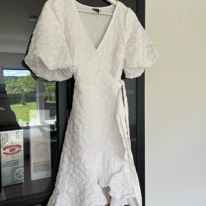 Vit omlottklänning - Fin vit somrig omlottklänning från Pieces. Blommönster. Storlek XS. Mycket bra skick