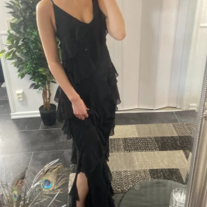 Volang klänning med slits - Jag säljer denna jättesnygga volang klänning med slits från Boohoo eftersom den inte har kommit till användning, helt oanvänd så mycket bra skick! Den har justerbara band. Passar till många omständigheter. Helt slutsåld! Nypris 627kr