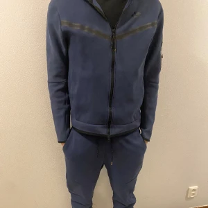 NIKE TECH Dress  - Säljer denna Nike Tech dress i strl M. Defekt på vänster knä ( se bild ) annars i gott skick. Byxa + Tröja för 1000kr, annars 500kr för byxa och 600kr för hoodie.  Kan mötas upp i Örebro, annars står köparen för frakten.