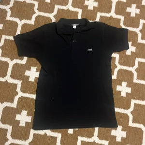 Lacoste polo t-shirt - En Svart Lacoste polo T-shirt, lite använd  Size Xs Bra pris Priset går att diskutera 👍