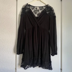 Svart klänning - Snygg svart klänning med flera detaljer som spets tyg, volanger & blommor. Står storlek xs men passar en S Fråga kring funderingar🌺