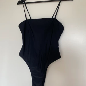 Svart baddräkt med hög benskärning  - Säljer en svart baddräkt från NA-KD med hög benskärning. Baddräkten är endast använd ett fåtal gånger och är i fint skick