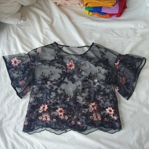 Genomskinlig blomtröja - Oklart vilket material, men broderade blommor på genomskinlig svart tyg.