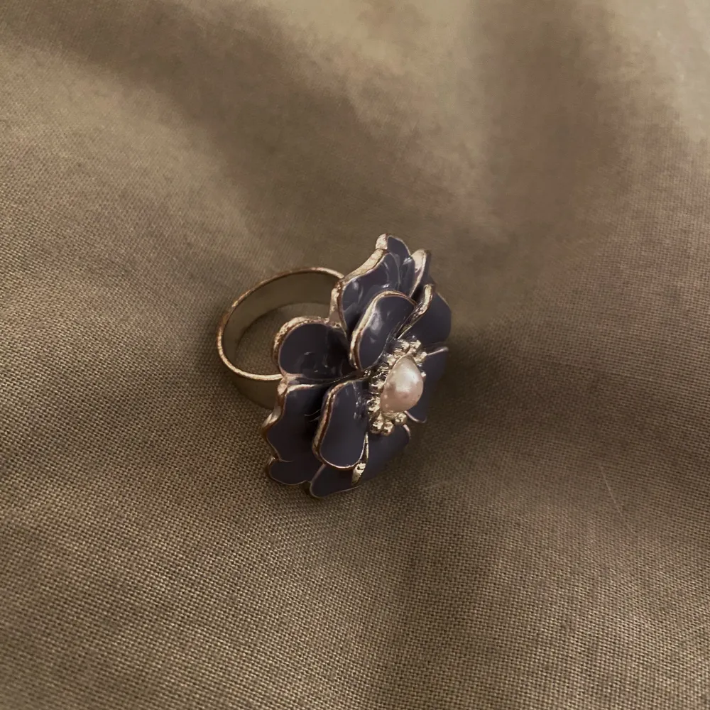 Blom ring i en jättefin blå färg med en pärla i mitten! Rostfri, den är använd och säljer för att den är för stor. Skick 8/10❣️. Övrigt.