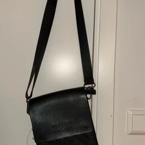 Hugo boss axelväska  - Tja! Jag säljer denna väska då den inte kommer till användning. Den är inte äkta! Skick 7/10 med lite defekter på framsidan. Tar gärna prisförslag. Skriv om ni har frågor!