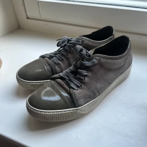 Lanvin skor - Fina grå/bruna lanvin skor som jag nu säljer. Skorna är väl använda och det finns en del slitage på dem men det återspeglas på priset. Storlek 7 motsvarar ca storlek 43.  Fler bilder kan skickas. Box eller kvitto finns ej kvar.
