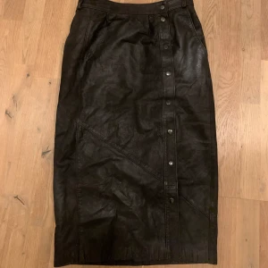 Brun skinn kjol - Brun lång skin kjol. Extremt snygg och passar med myxket. Den knäpps upp och är knappt använd.