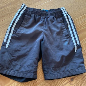 Jag säljer ett par adidas badbyxor/badshorts. Tveka inte på att fråga frågor och jag kan absolut diskutera pris! - Inga defekter, fickor på båda sidorna och en svart adidas logga. Finns tecken på användning men är inte sliten.