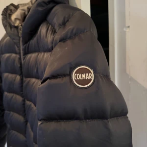 Colmar jacka dam - Jättefin marinblå jacka från Colmar med beige insida. Ena fickan är tyvärr trasig i dragkedjan, därav priset. I övrigt bra begagnat skick!
