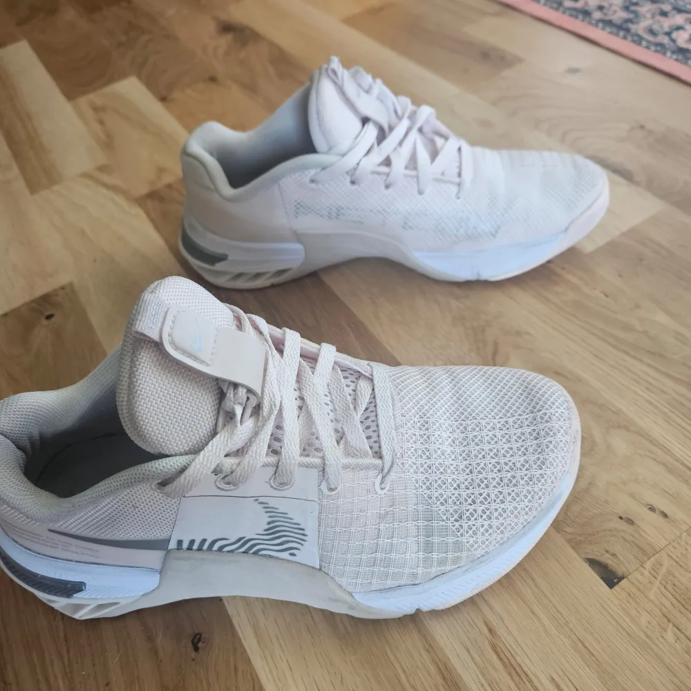 Ett par ljusrosa Nike React med snörning och en diskret Nike-logga.. Skorna har en mesh-överdel för andningsförmåga och en stabil sula för komfort. Mycket bra skick. Skor.