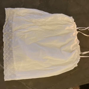 jättefint vit linne med broderade blommor längst ner🤍 - Ett jättefint vit linne med broderade blommor längst ner  o små volanger från name it🤍storlek 146-152, jättebra skick använt få gånger. Säljs för de inte kommer till användning, är jättefint🤍
