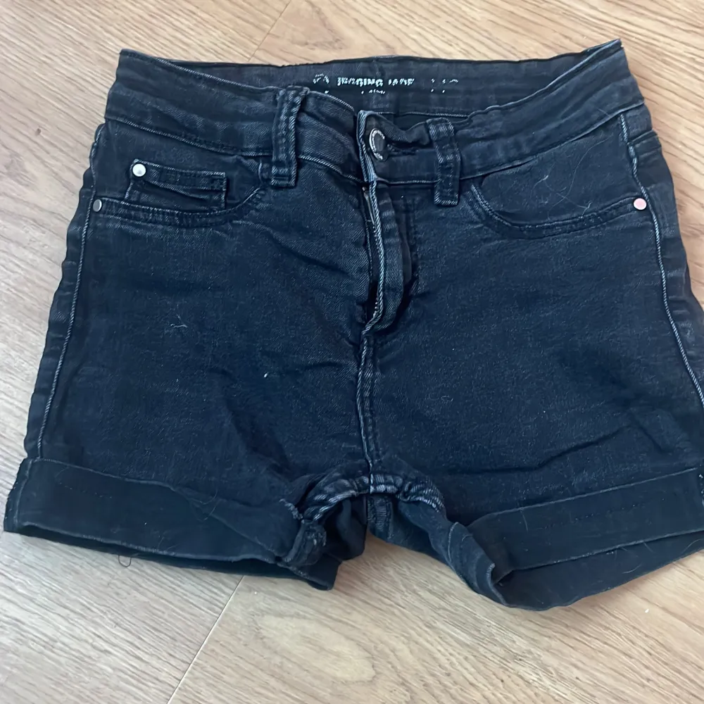 Ett par svarta jeansshorts med låg midja. Shortsen har en dragkedja och knapp framtill samt fickor både fram och bak. De är i ett välanvänt skick.. Shorts.