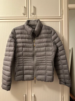 Täckjacka  - Storlek L  Grå med gulddetaljer 