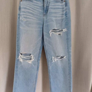 Ljusa slitna jeans - Säljer ett par ljusa jeans med slitningar på låren och knäna. De är högmidjade och har en straight fit. Perfekta för en avslappnad och trendig look!