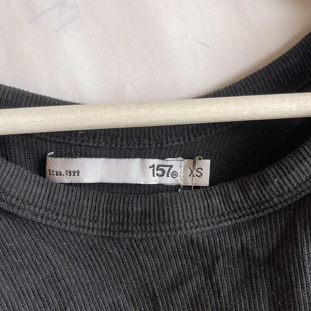 Säljer en svart ribbad croppad linnetopp från 157 i storlek XS. Toppen är ärmlös och perfekt för sommaren. Den är i nyskick och har en tight passform. Perfekt för både vardag och fest!. Yläosat.