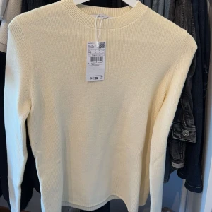 Gul stickad tröja från Gina Tricot - Säljer en superfin stickad tröja från Mango. Den är i nyskick och har en normal passform. Perfekt för höst och vår! Tröjan har långa ärmar och en rund halsringning. Den är både mysig och stilren, perfekt för att hålla sig varm och snygg på samma gång. 🌼