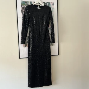 Svart långklänning i paljetter - Långklänning i paljetter. Använd endast en gång. Som ny. Öppen rygg och figursydd