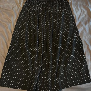 Svart prickig kjol från Jacqueline de Yong - Säljer en svart kjol med vita prickar från Jacqueline de Yong. Kjolen är lång och har en elastisk midja. Fint skick. Katt finns i hemmet, men allt jag säljer är nytvättat och rollat ✨💛
