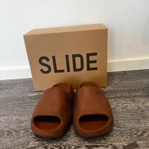 Yeezy slides - Säljer ett par extremt sköna yeezy slides storlek 42 i färgen Flax då de tyvärr har blivit försmå. Defekterna ser ni på bild nr 3 och 4.  Men dem är fortfarande lika sköna som när dem var nya. Priset är inte huggget i Sten vid snabb affär.