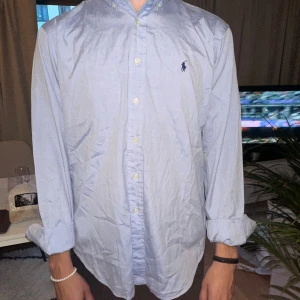 Ralph Lauren skjorta - Säljer min ljusblå Ralph Lauren skjorta, perfekt till sommaren/hösten. Den är sparsamt använd och finns inga tecken på användning. Hör av dig vid fler frågor!