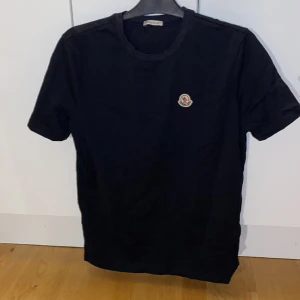 Moncler T-shirt - Säljer en helt ny Moncler T-shirt, pga den inte kommer till användning. Inte original. Väldigt bra och skönt material! Färgen är väldigt väldigt mörkblå, ifall det inte syns på bilderna. Skick: Ny Storlek: M
