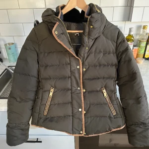 Zara jacka - Mörkgrön dunjacka från Zara i storlek medium. Sparsamt använd. Varm och passar vinter och höst. Päls på insidan av kragen och fina gulddetaljer. Nypris ca 1200kr.